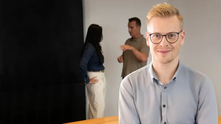 Young man leaning on the table in the office setting.